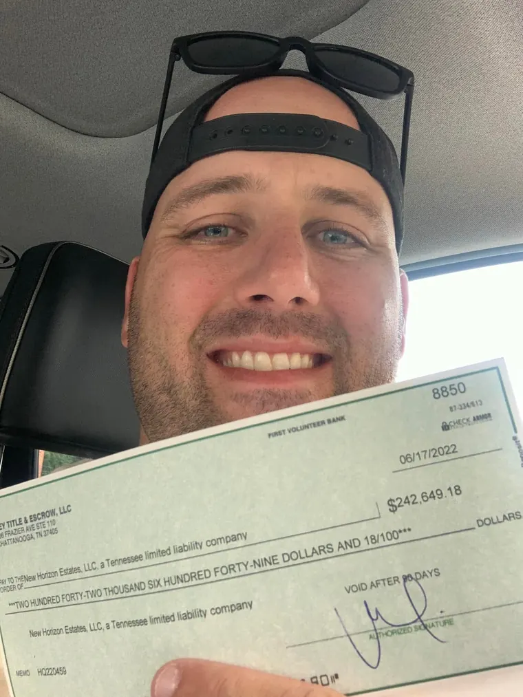 Erik in his truck holding the closing check from the flip &mdash; First Volunteer Bank, 06/17/2022, $242,649.18, payable to New Horizon Estates, LLC.